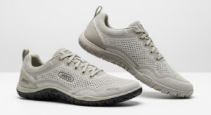 A pair of light grey Xero Shoes featuring mesh uppers, lace closures, and textured rubber soles. Designed for walking, they provide all-day comfort with ventilation holes and a minimalistic style. The "Xero" brand name is displayed on the shoes.