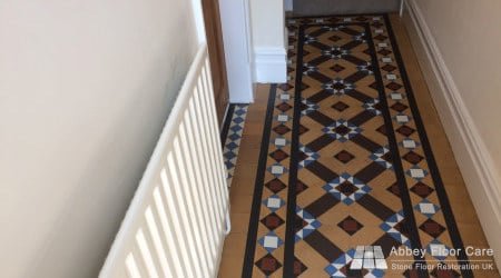 Victorian tiled hallway showing worn borders, faded colours and visible surface deterioration